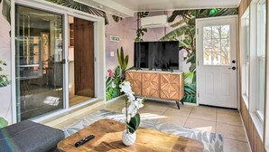 A living room with a sliding glass door, a wooden cabinet, a TV, and a potted orchid on a coffee table. - Emerald Coast Vacation Rental: 1 Mi to Beach (Shalimar)