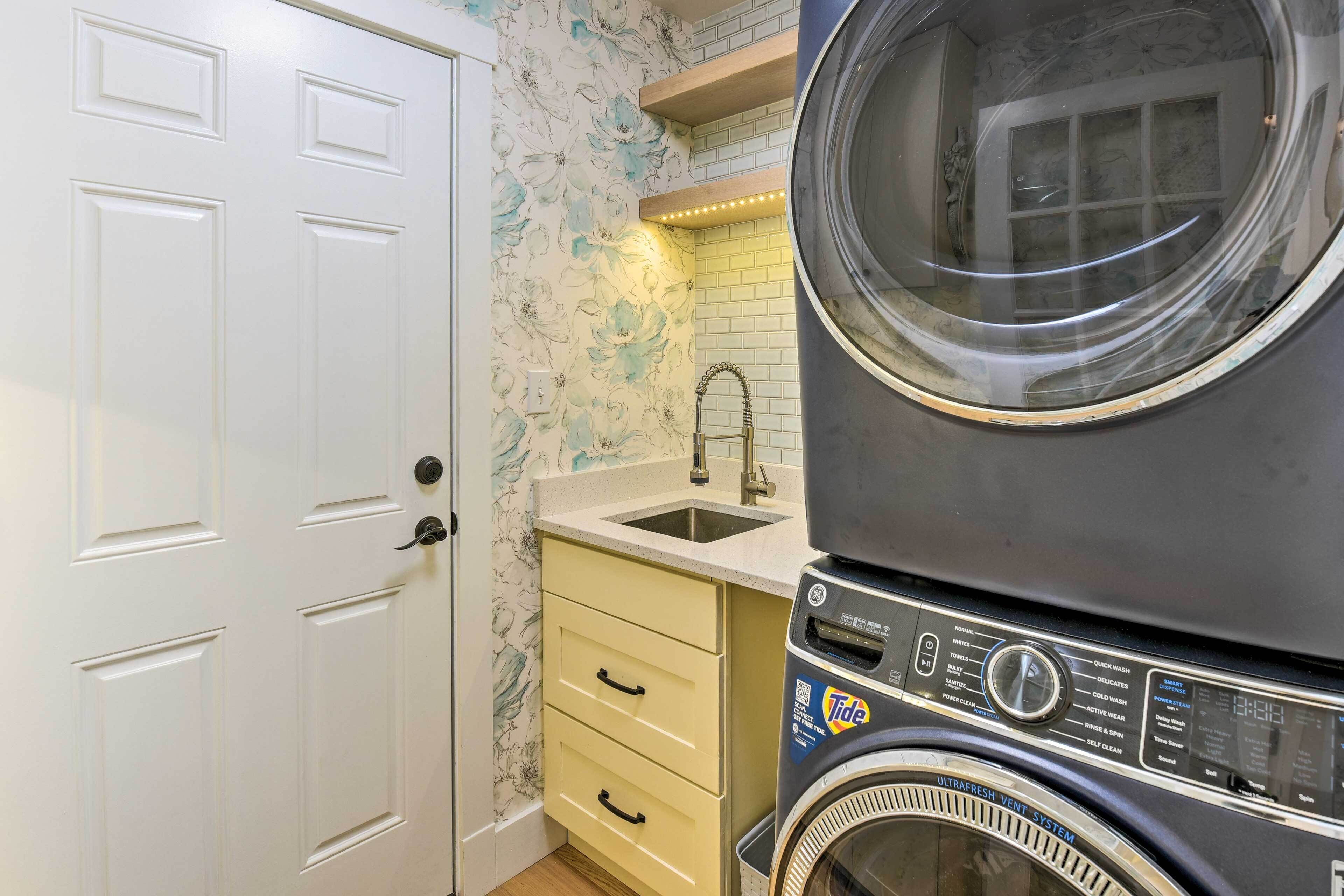 A compact laundry area with a front-loading washing machine, a sink, and a small cabinet.
