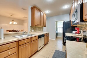 Una cocina moderna con armarios de madera, lavavajillas, estufa y microondas.