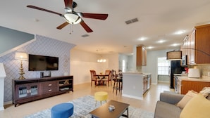 A modern living room with a television, sofa, ottoman, and coffee table.