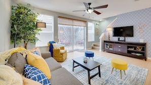 A modern living room with a sofa, a coffee table, a TV, and a ceiling fan.