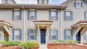 A multi-story residential building with a central entrance, symmetrical windows, and a tiled roof.