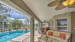 A covered patio with a pool, outdoor furniture, and a ceiling fan. - Lanai & Heated Pool: Stunning Cape Coral Getaway (Cape Coral)