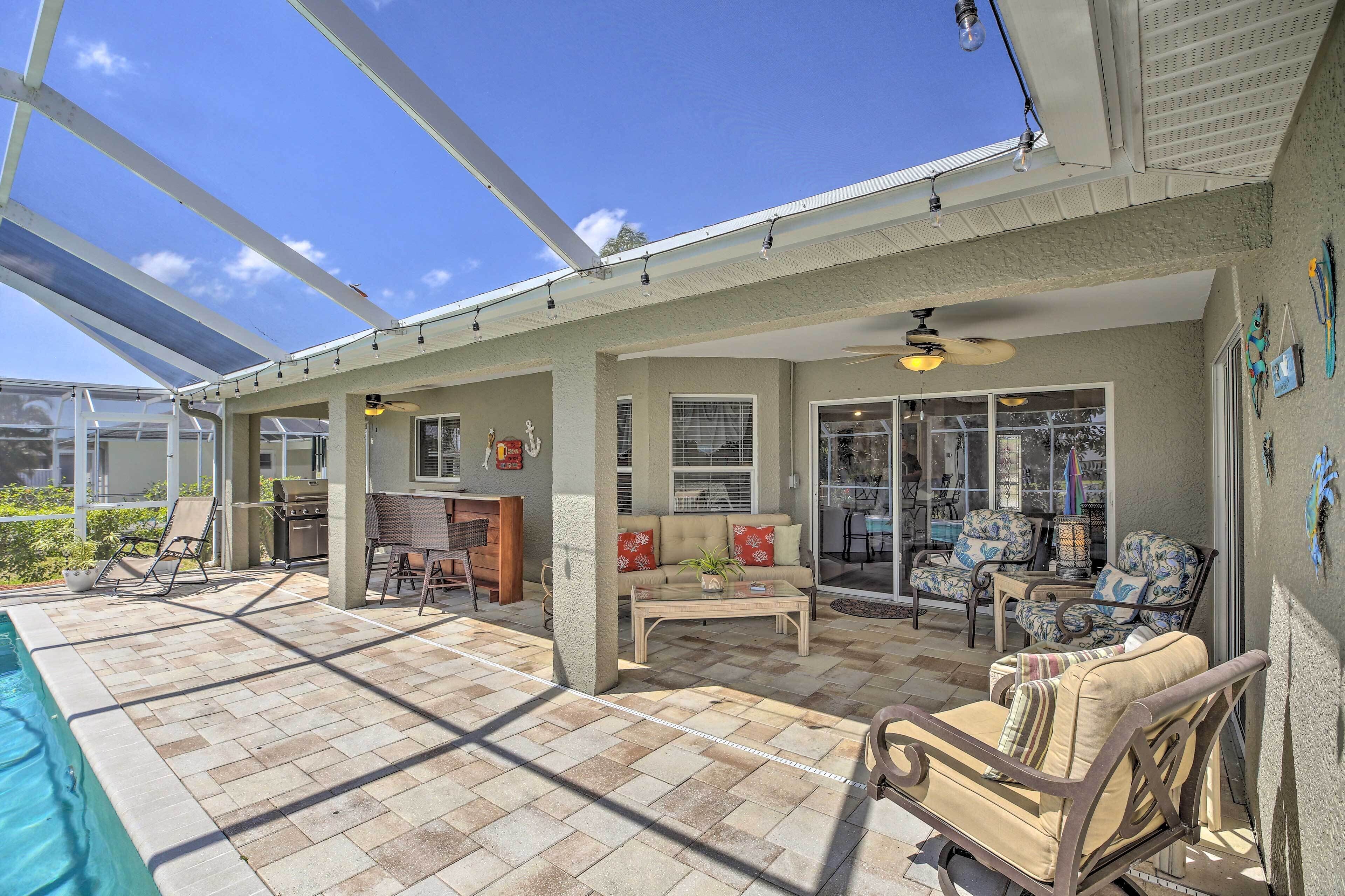 A covered patio with a pool, outdoor seating, and a grill area.