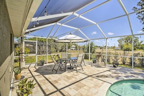 A covered patio area with a pool, outdoor furniture, and potted plants. - Lanai & Heated Pool: Stunning Cape Coral Getaway (Cape Coral)