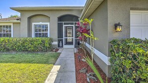 A residential house with a front entrance, a driveway, and a well-maintained garden with various plants. - Lanai & Heated Pool: Stunning Cape Coral Getaway (Cape Coral)