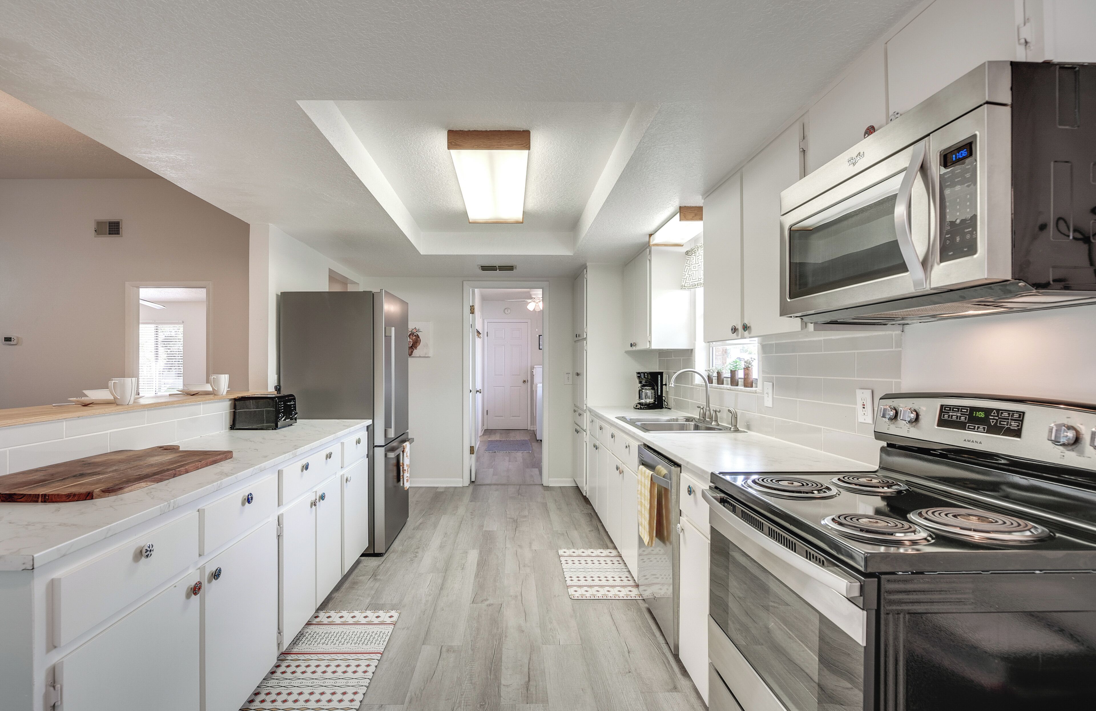 Une cuisine moderne avec des meubles blancs, une cuisinière en acier inoxydable, un four à micro-ondes et un réfrigérateur.