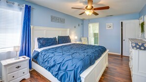 Une chambre à coucher avec un lit, une table de chevet et un ventilateur de plafond.