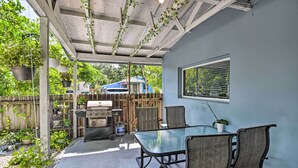 A covered patio with a glass table and chairs, a grill, and potted plants. - Shady & Eclectic Fort Lauderdale Dwelling w/ Yard! (Fort Lauderdale)