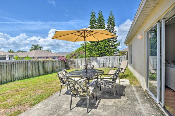 A patio with a round table and chairs, a yellow umbrella, and a wooden fence. - Family-friendly Home ~ 6 Mi to Beach or Golf (Edgewater)