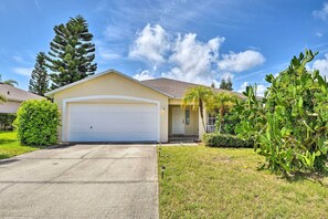 A single-story house with a garage, surrounded by well-maintained lawns and a variety of trees. - Family-friendly Home ~ 6 Mi to Beach or Golf (Edgewater)