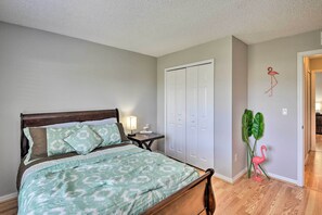 A bedroom with a bed, nightstand, lamp, closet, and a wall decoration. - Family-friendly Home ~ 6 Mi to Beach or Golf (Edgewater)