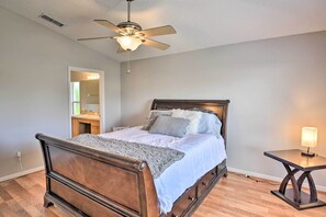A bedroom with a wooden bed, a ceiling fan, a nightstand, and a mirror. - Family-friendly Home ~ 6 Mi to Beach or Golf (Edgewater)