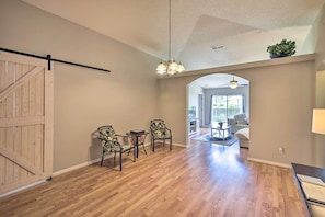 A spacious room with hardwood flooring, a dining area with two chairs and a table, and a large wooden door. - Family-friendly Home ~ 6 Mi to Beach or Golf (Edgewater)
