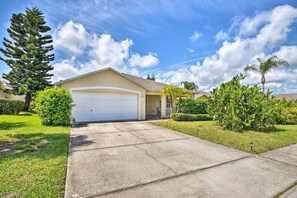 A single-story house with a garage, surrounded by well-maintained lawns and various trees. - Family-friendly Home ~ 6 Mi to Beach or Golf (Edgewater)