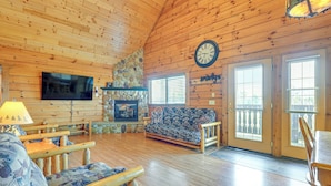 A cozy cabin interior with a stone fireplace, wooden furniture, and a large clock on the wall. - Resort Cabin w/ Lake Access in Central Warrens! (Warrens)