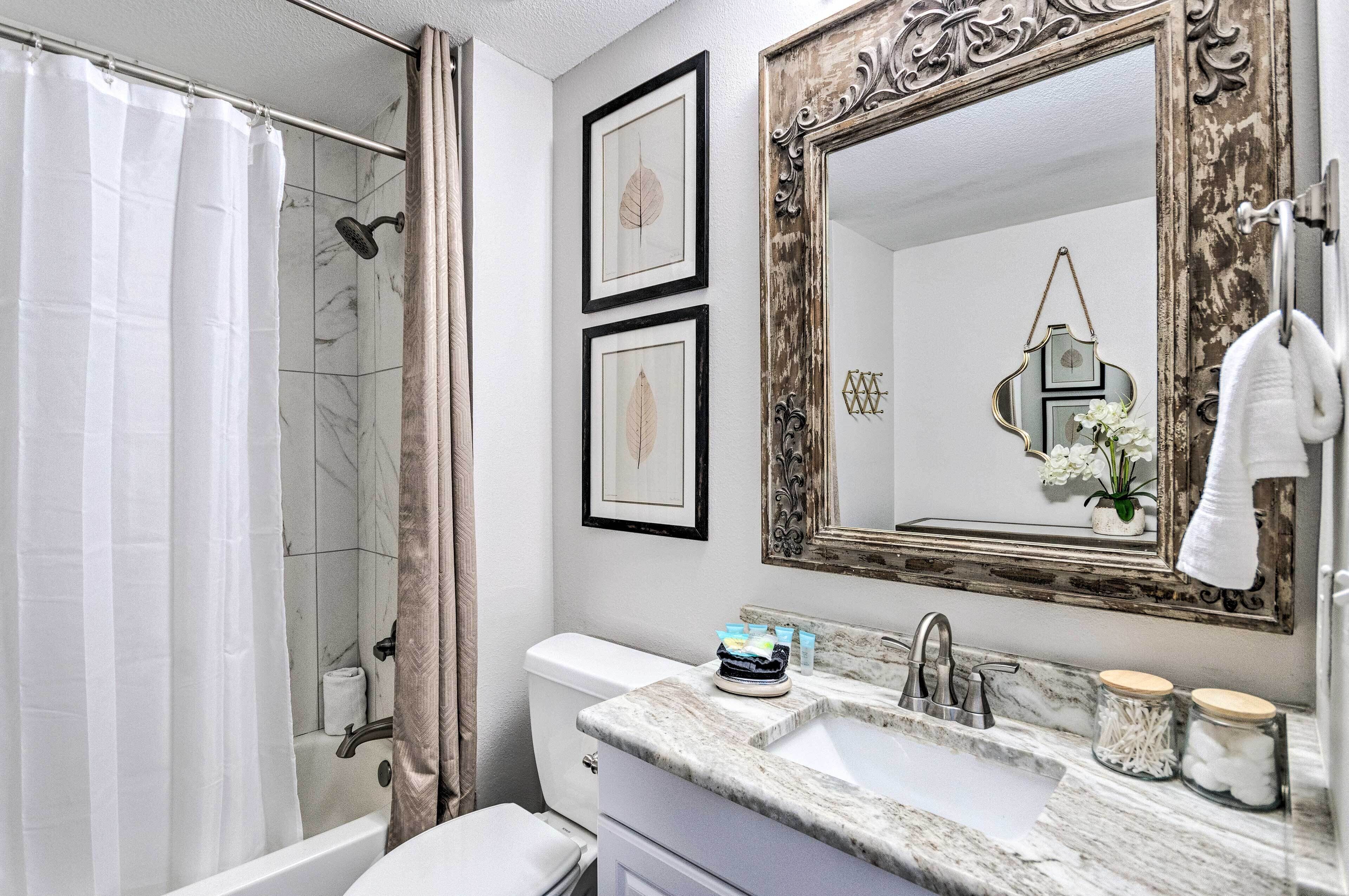 A bathroom with a shower, toilet, sink, and a large mirror.
