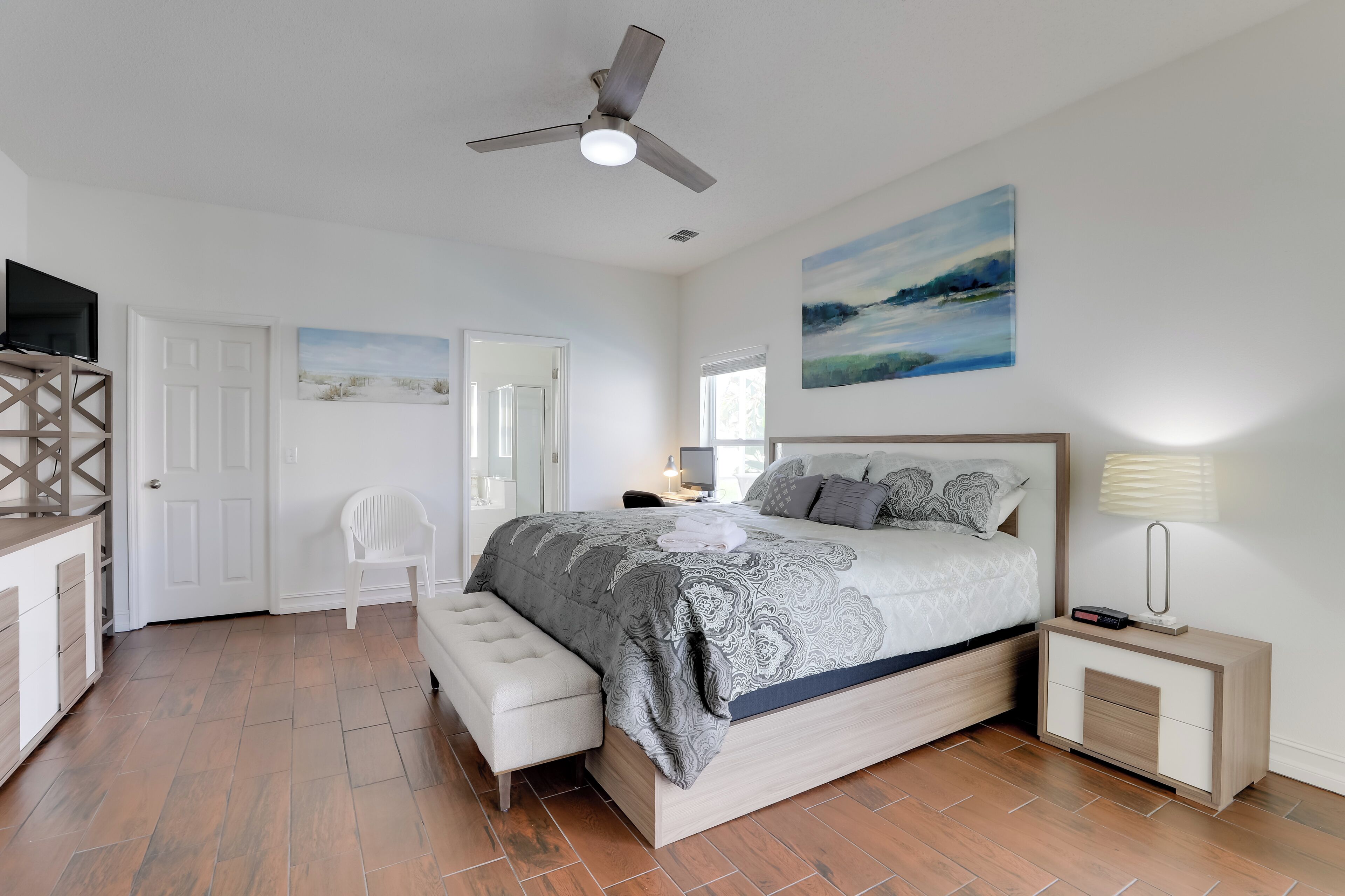 A bedroom with a bed, bedside table, nightstand, and a ceiling fan.