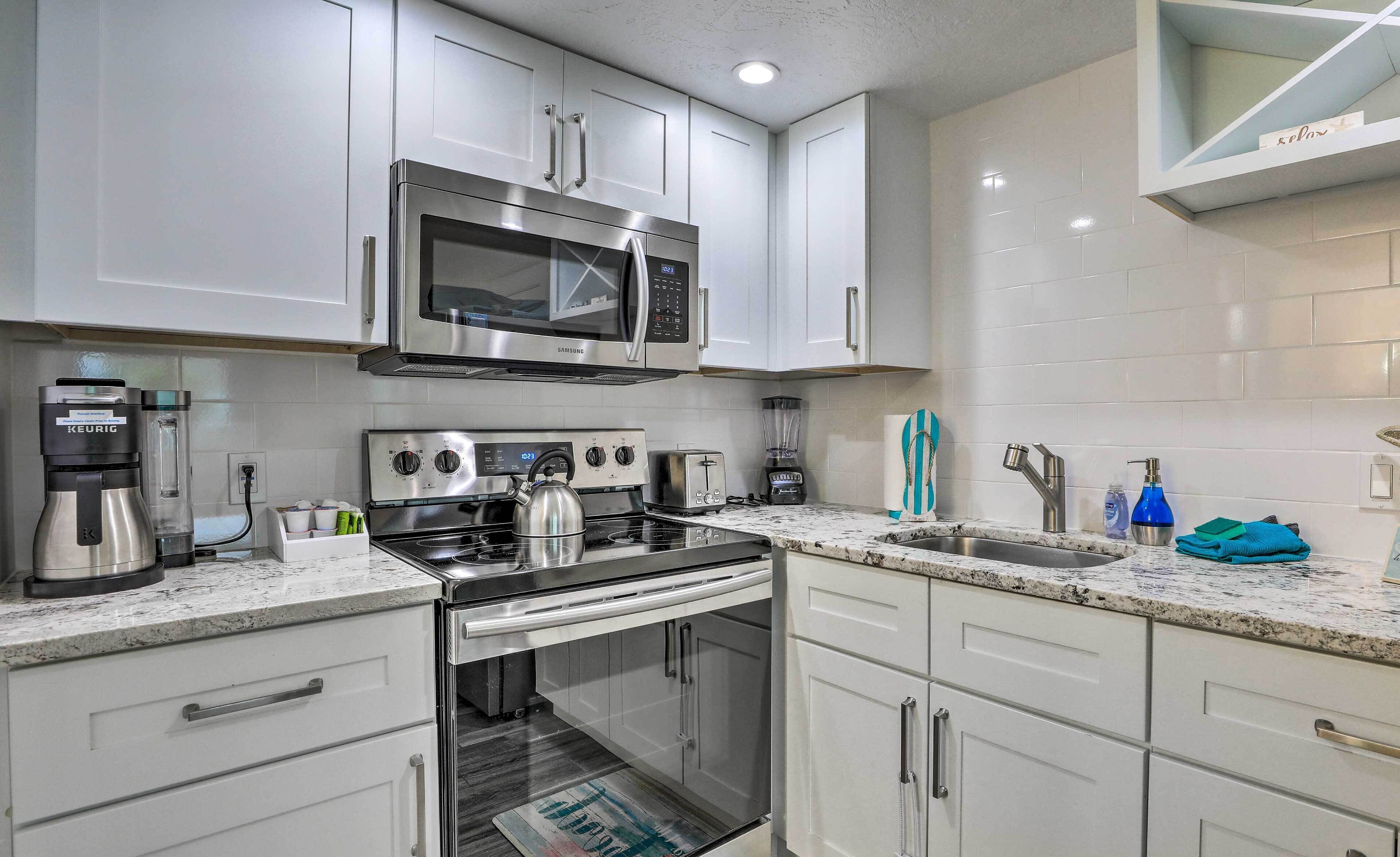A modern kitchen with white cabinets, stainless steel appliances, a built-in oven, and a microwave.