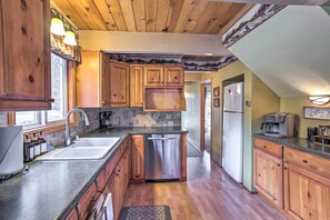 A kitchen with wooden cabinets, a stainless steel dishwasher, and a coffee maker. - 'château Forêt' in Big Bear w/ Hiking Trail Access (Big Bear City)