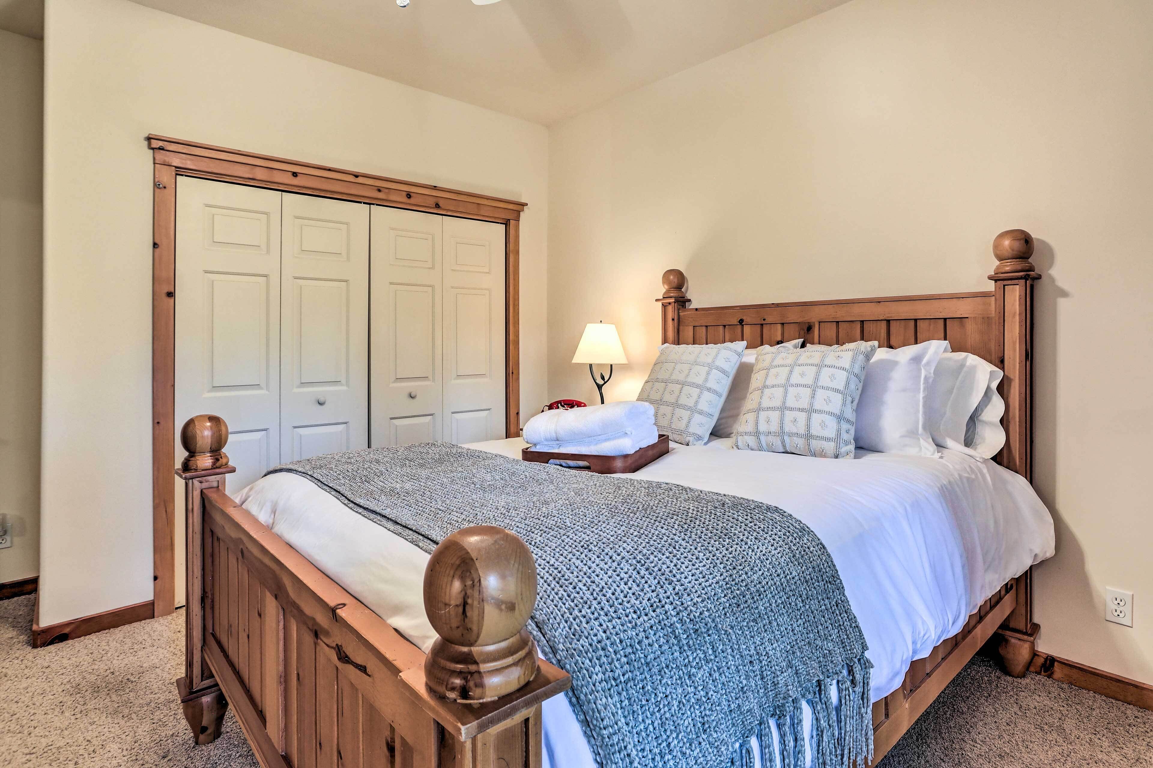 A bedroom with a wooden bed, a nightstand, a lamp, and a closet with double doors.
