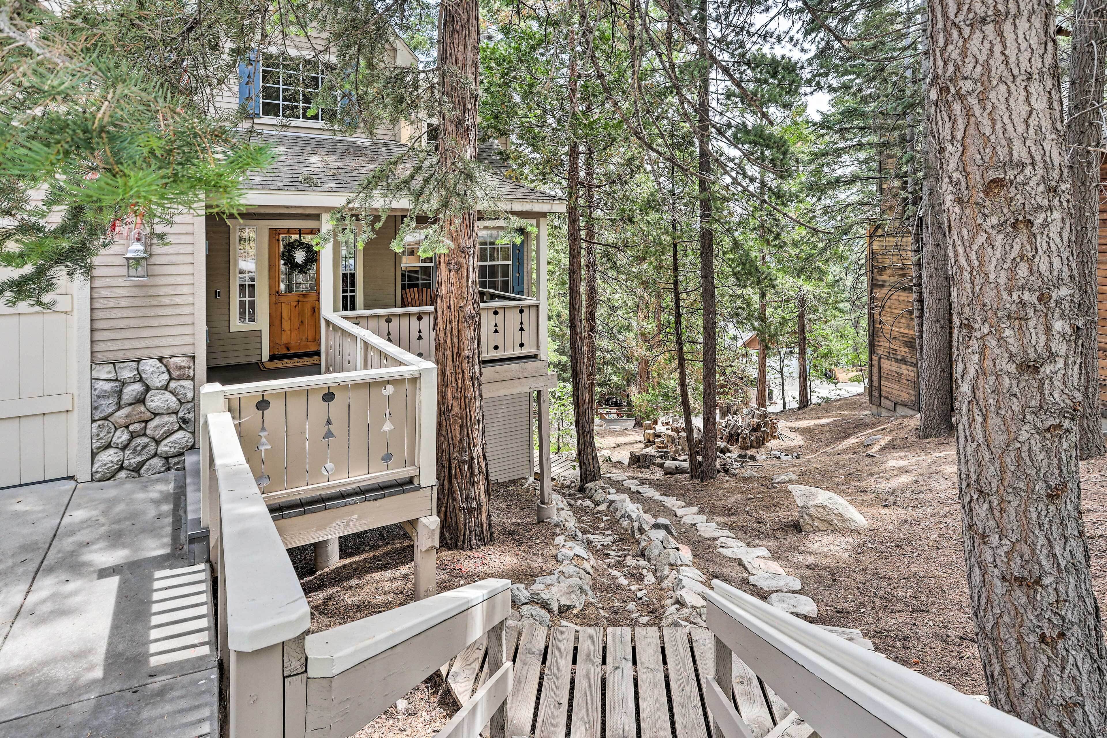 A cabin with a porch, stone wall, and wooden deck.