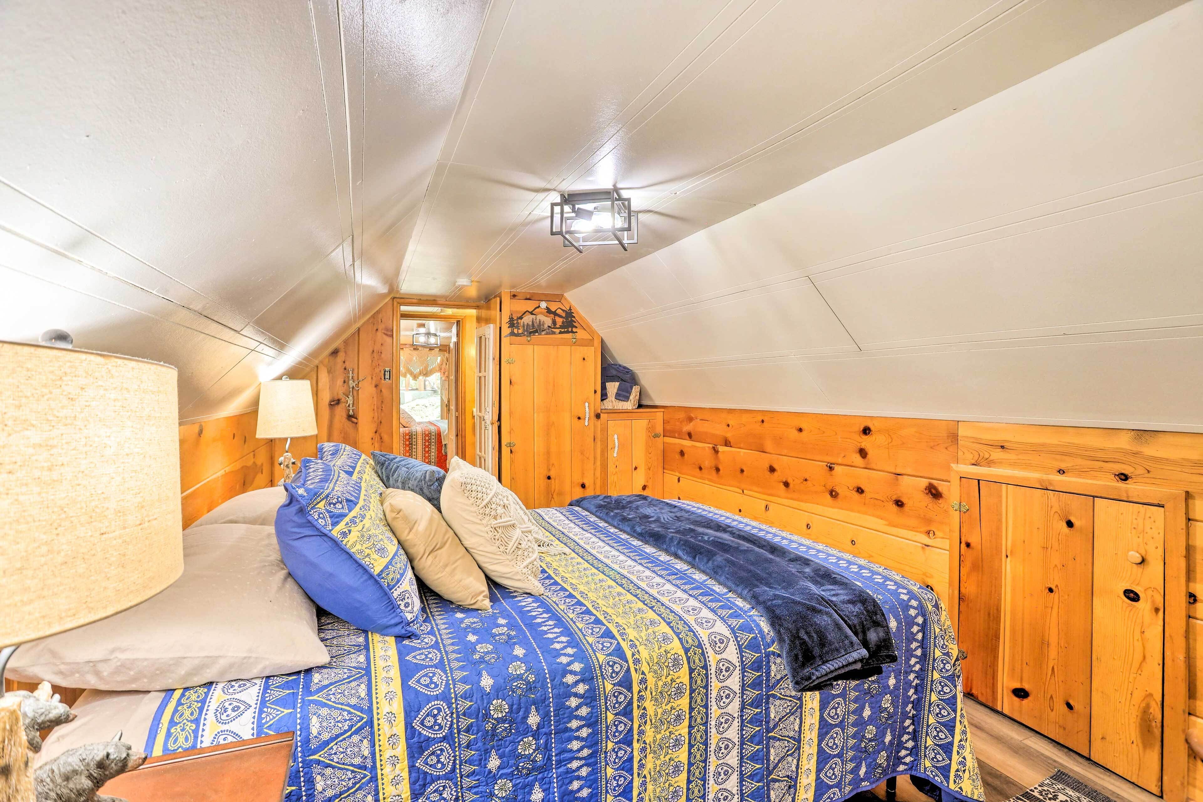 Une chambre confortable avec un lit, des murs en bois et un luminaire au plafond.