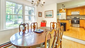 A dining room with a wooden table and chairs, a chandelier, and a view of the kitchen. - Game Room + Patio: Quiet Centerville Beach Base (Centerville)