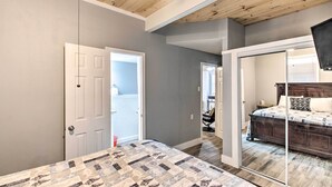 Une chambre avec un grand lit, un plafond en bois et une porte-fenêtre coulissante donnant sur une autre pièce.