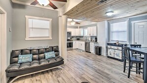 Un vaste espace de vie comprenant un canapé en cuir, un plafond en bois et une table à manger avec des chaises.