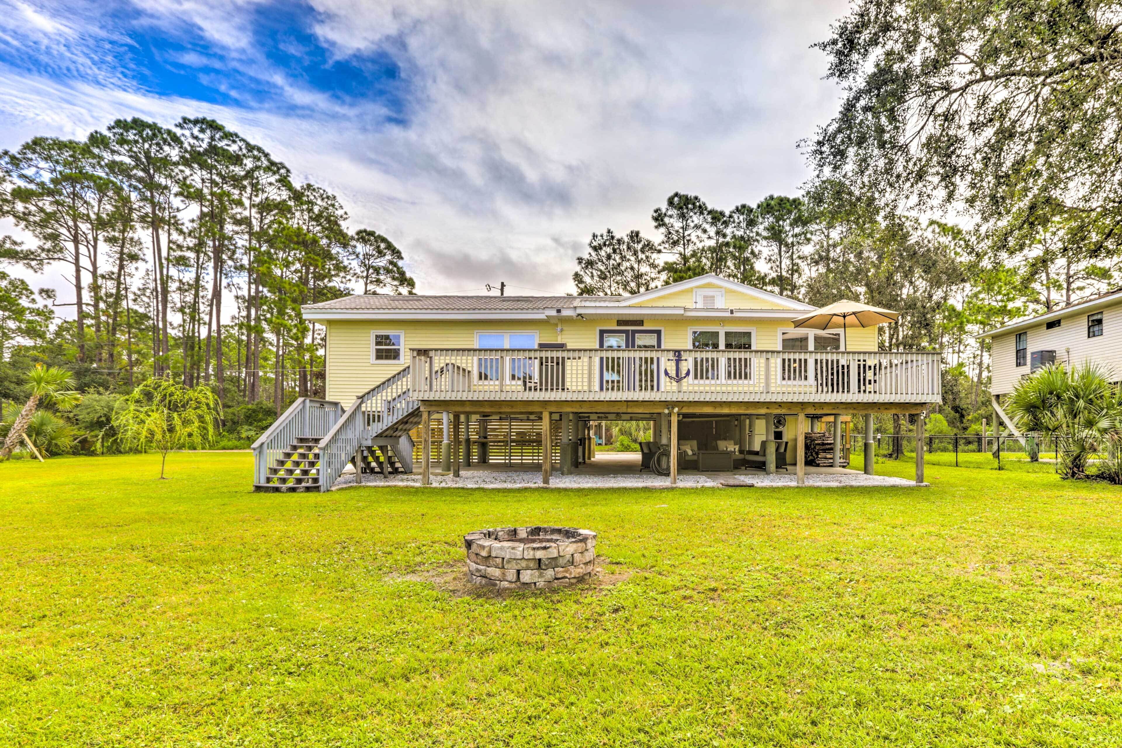 A two-story house with a covered porch, a stone fire pit, and a staircase leading to the upper level.