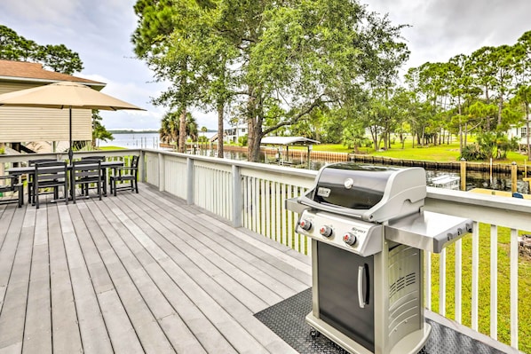 A wooden deck with a grill, outdoor seating, and a view of a lake. - Waterfront Home: Spectacular On-site Fishing! (Panacea)