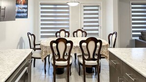 Un coin repas comprenant une table ronde, six chaises et une cuisine équipée de placards et d’un plan de travail.