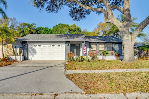 A single-story house with a garage, a large tree in front, and a well-maintained lawn.