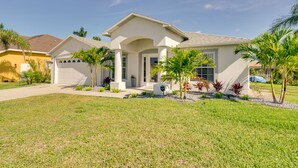 A modern two-story house with a white exterior, a covered front porch, and a well-maintained lawn. - Canal-front Cape Coral Home Rental: Pool, Lanai! (Cape Coral)