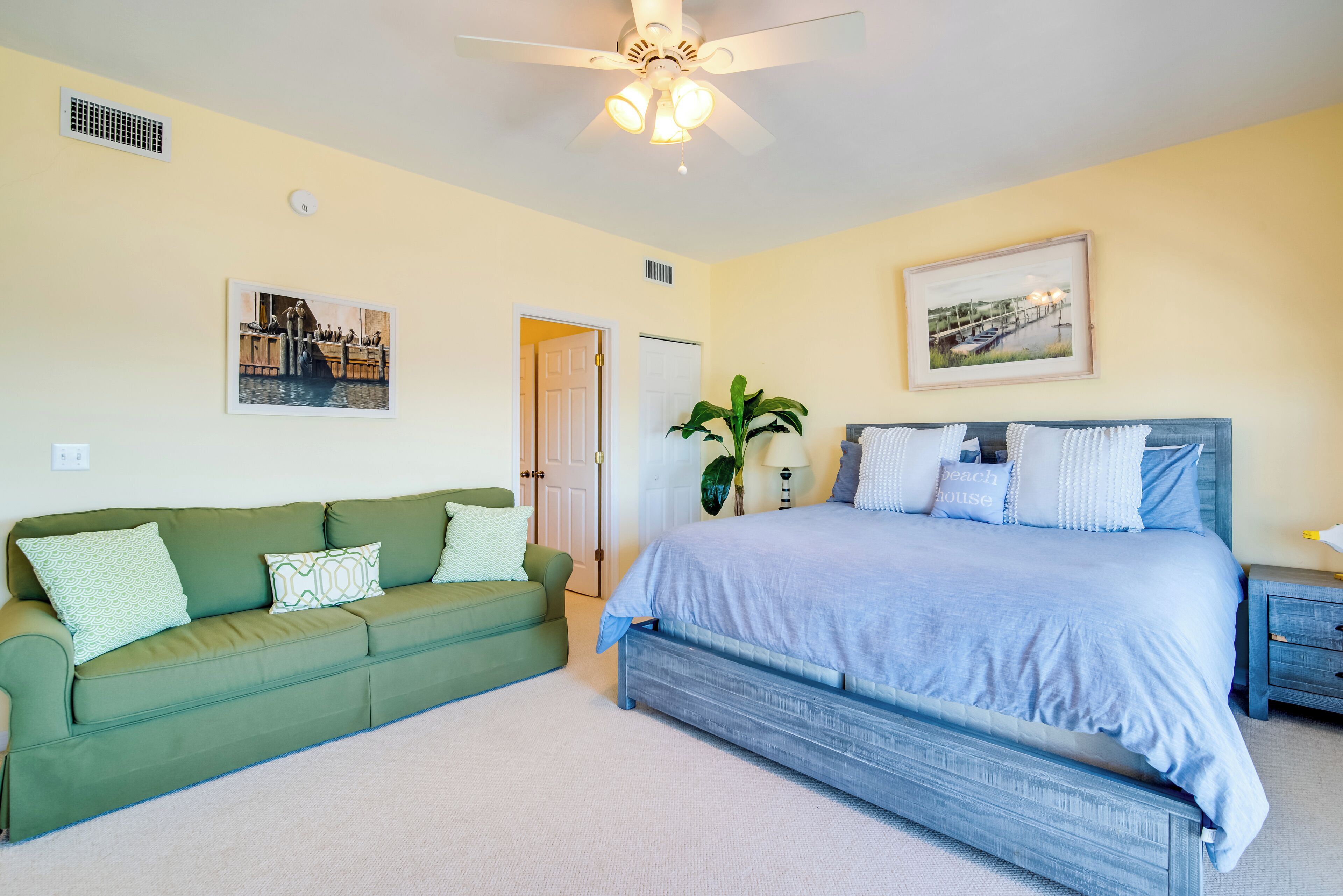 A bedroom with a bed, a green sofa, and a ceiling fan.