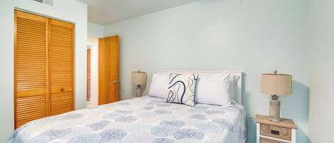 A bedroom with a bed, a nightstand, a lamp, a ceiling fan, and a wooden wardrobe.