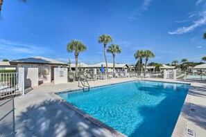 A swimming pool with clear blue water, surrounded by palm trees and lounge chairs. - Pool Access + Screened Porch: Sebring Resort Home (Sebring)