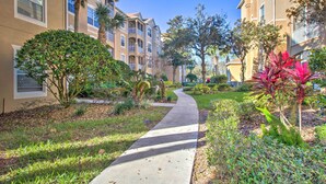 A pathway leading through a residential area with multi-story buildings, surrounded by well-maintained greenery and palm trees. - Resort Condo in Kissimmee ~ 3 Mi to Disney! (Kissimmee)