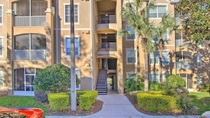 A multi-story apartment building with balconies, a central staircase, and a well-maintained garden. - Resort Condo in Kissimmee ~ 3 Mi to Disney! (Kissimmee)