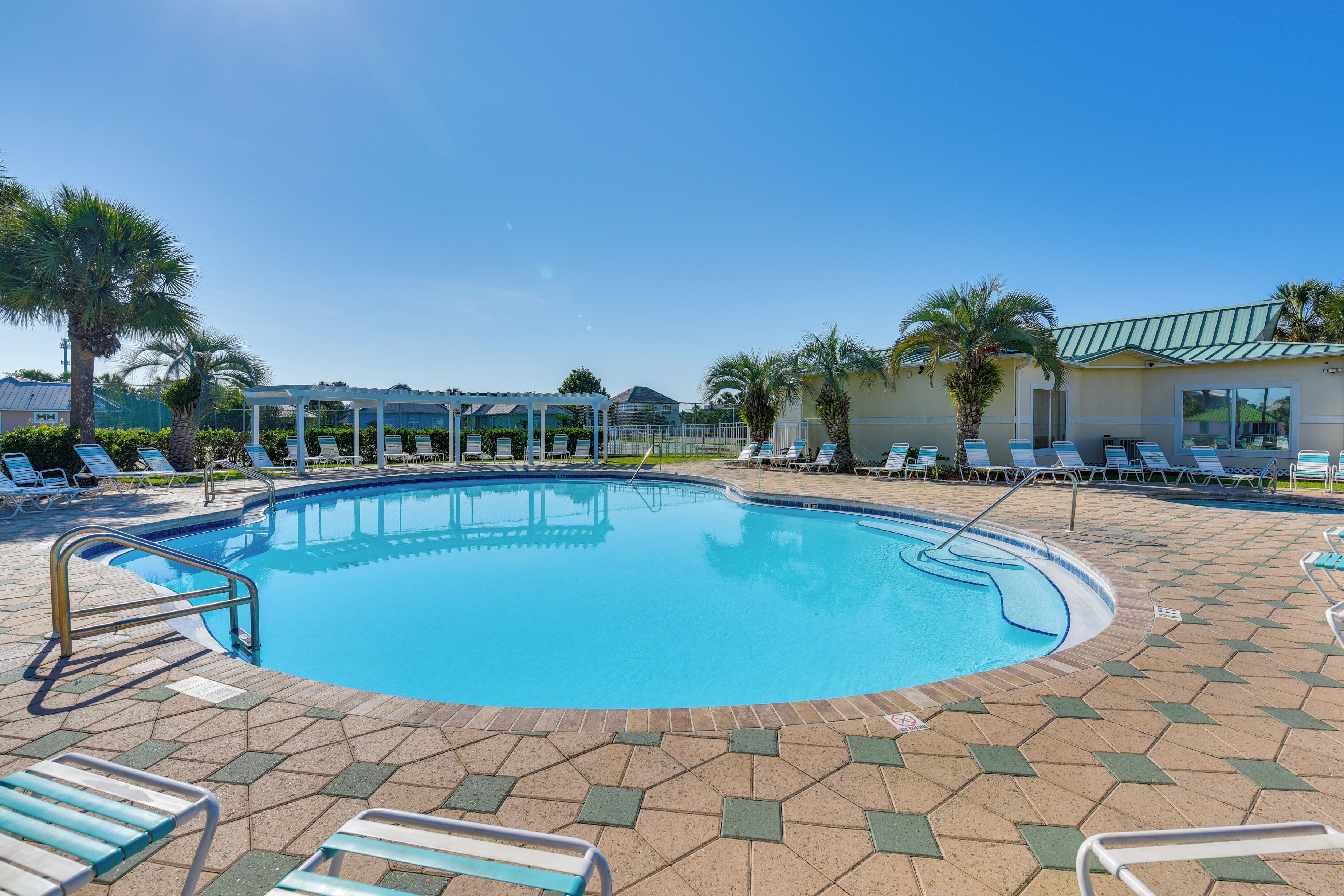 A swimming pool with lounge chairs and palm trees.