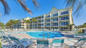 A hotel with a swimming pool surrounded by lounge chairs and palm trees. - Well-appointed Family Condo on Miramar Beach! (Miramar Beach)