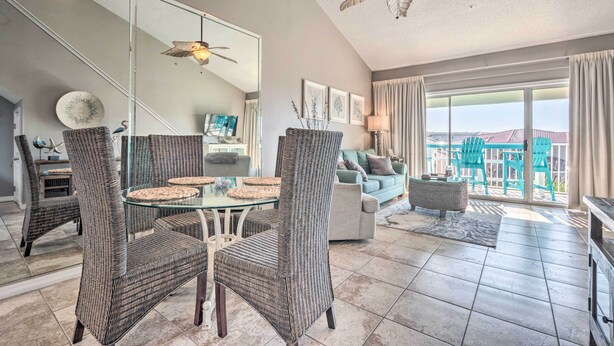 A spacious living area with wicker furniture, a glass dining table, and a balcony with a view. - Well-appointed Family Condo on Miramar Beach! (Miramar Beach)