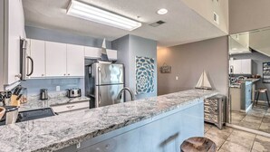 A modern kitchen with granite countertops, stainless steel appliances, and a central island with stools. - Well-appointed Family Condo on Miramar Beach! (Miramar Beach)