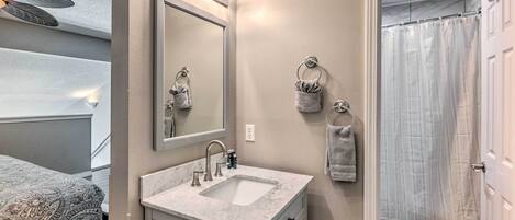 Un bagno con un lavandino in marmo, uno specchio grande e una tenda da doccia.