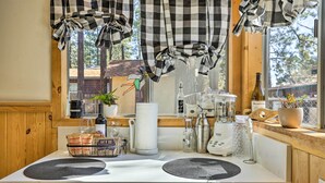 Une cuisine avec une fenêtre, une machine à café, une bouteille et une plante.
