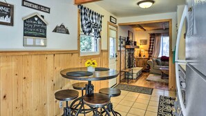 Une cuisine chaleureuse avec des murs en bois, une table ronde entourée de tabourets et un réfrigérateur.