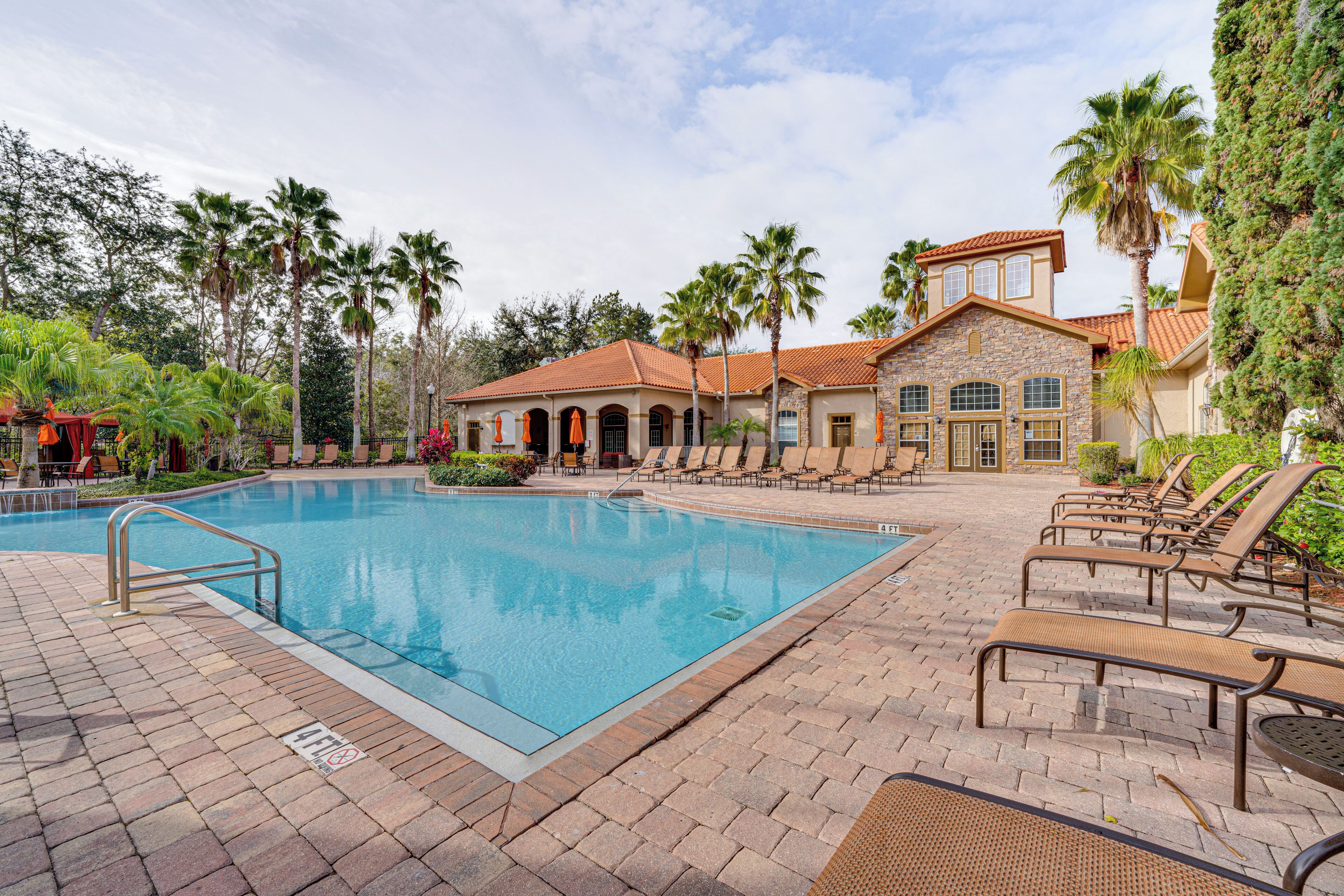 A swimming pool with lounge chairs and a building with a tiled roof.