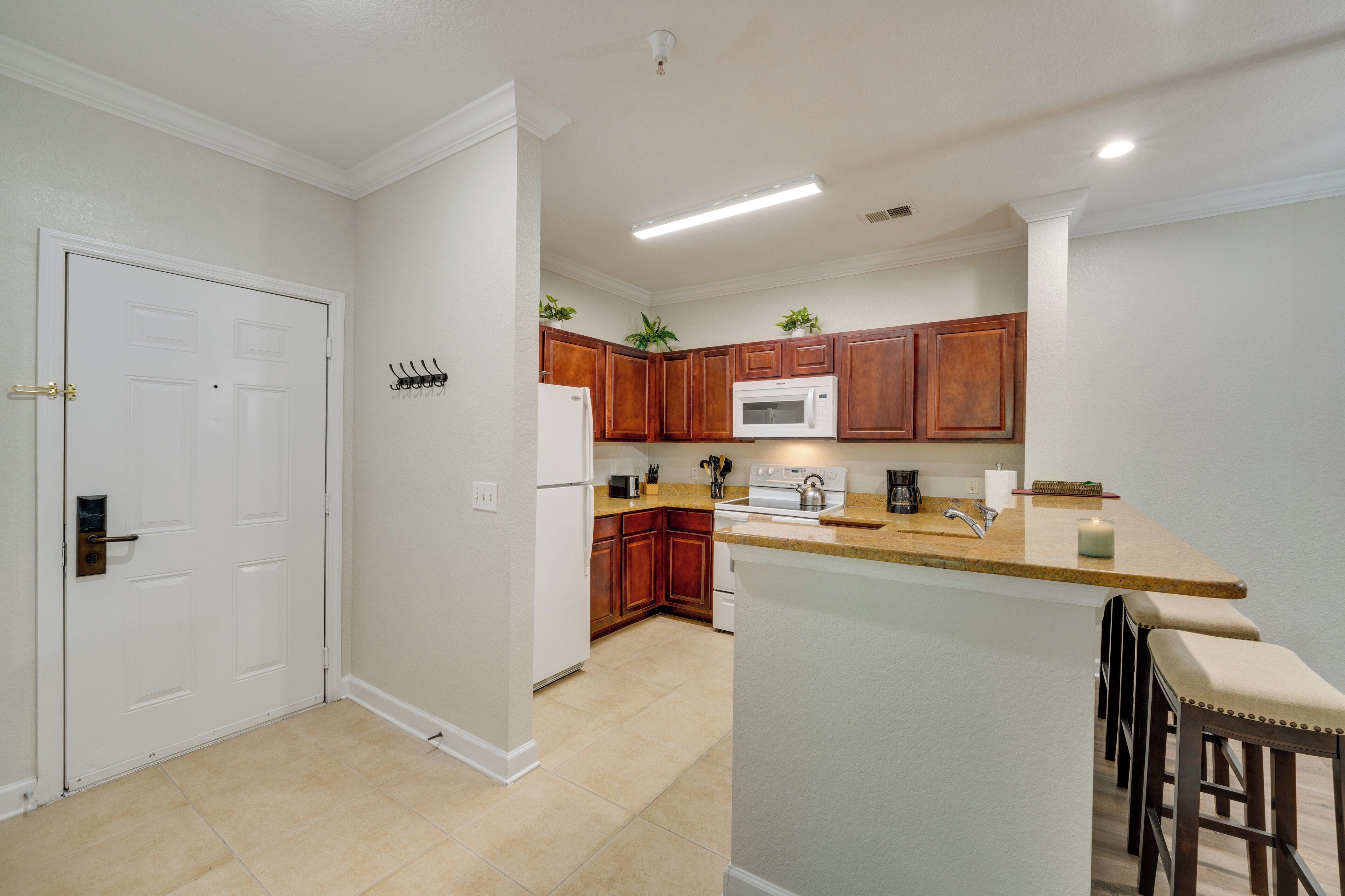 A modern kitchen with wooden cabinets, a microwave, and a built-in island with bar stools.