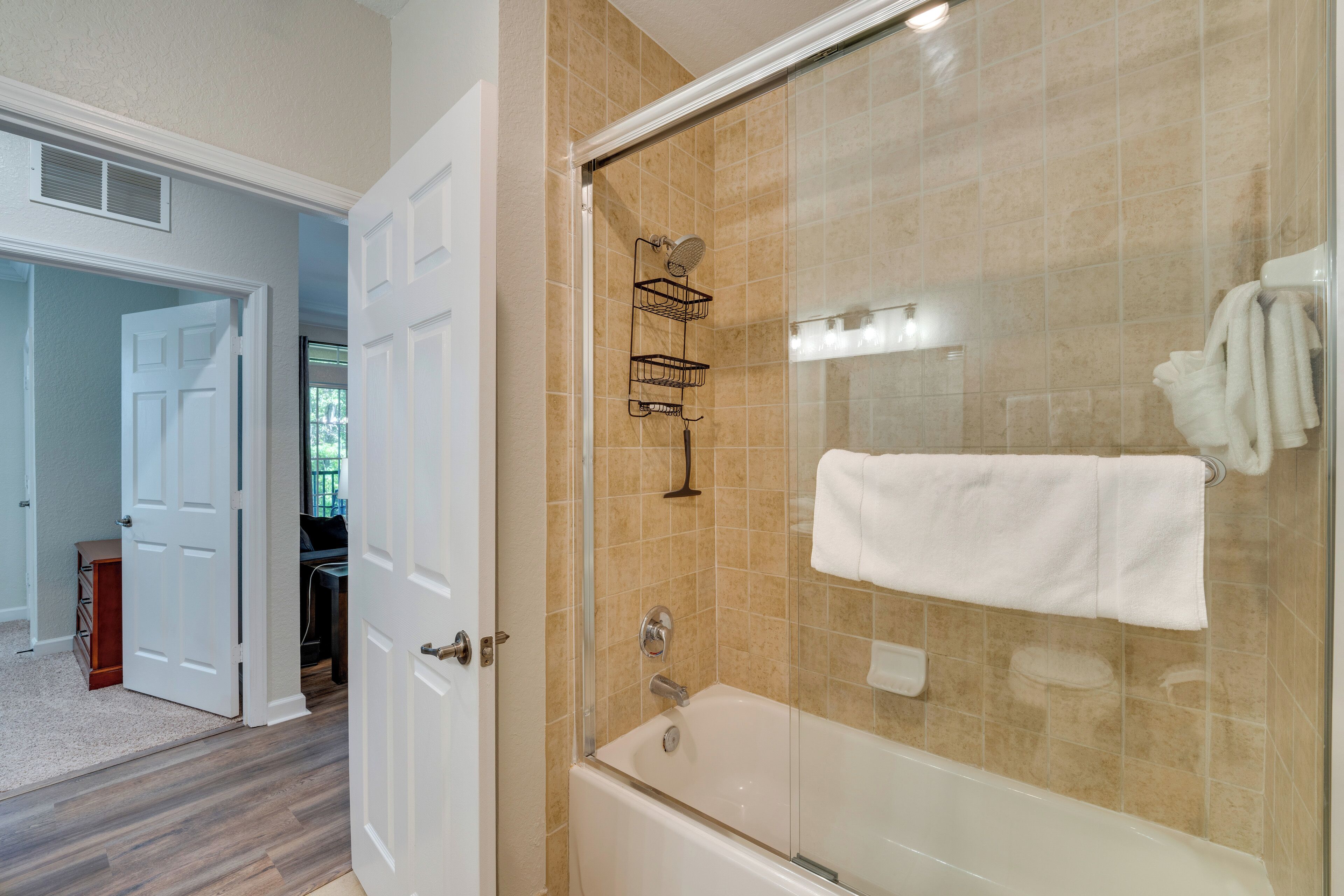 A modern bathroom with a glass-enclosed shower, a white bathtub, and a towel rack.